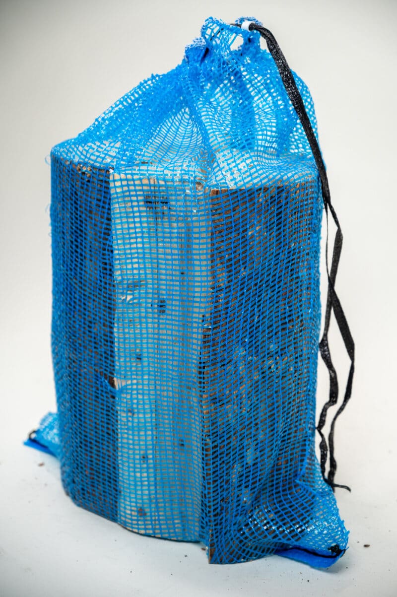 A blue bag with a white sign reading "Firewood 24/7" displayed prominently on the front.