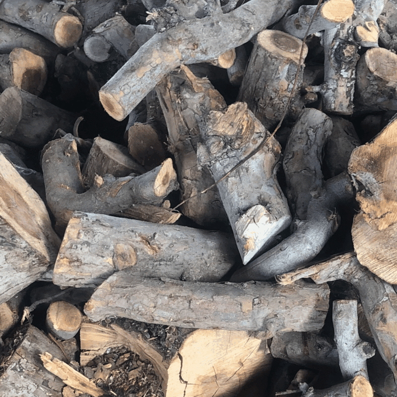A pile of apple wood logs and pieces, labeled as firewood available 24/7.