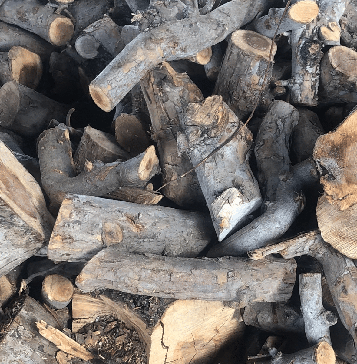 A pile of apple wood logs and pieces, labeled as firewood available 24/7.