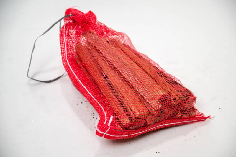 A bag of red sticks labeled "Firewood 24/7" on a white background, showcasing its blank bottom design.