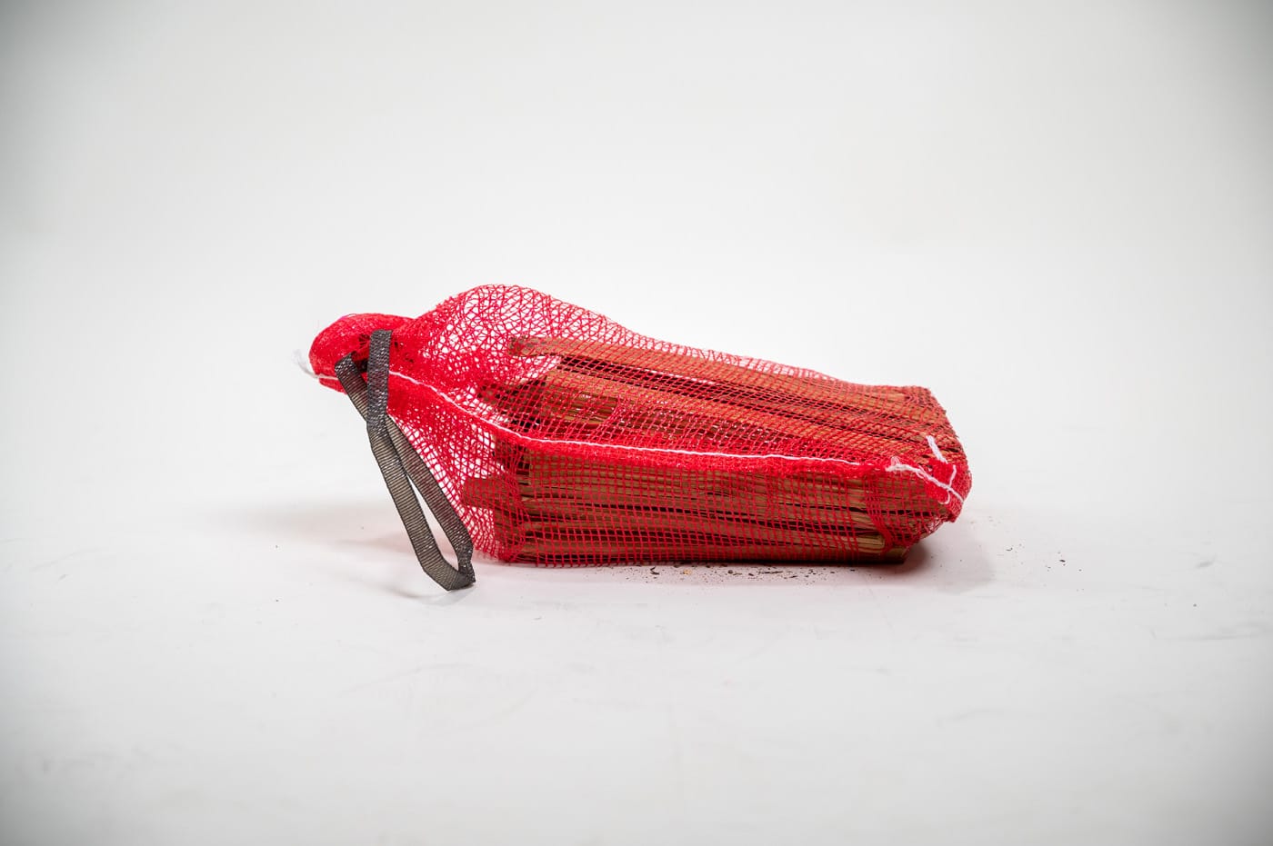 A red bag of firewood sticks on a white background, labeled "Firewood 24/7 - Red Bag Bottom Side Wide."