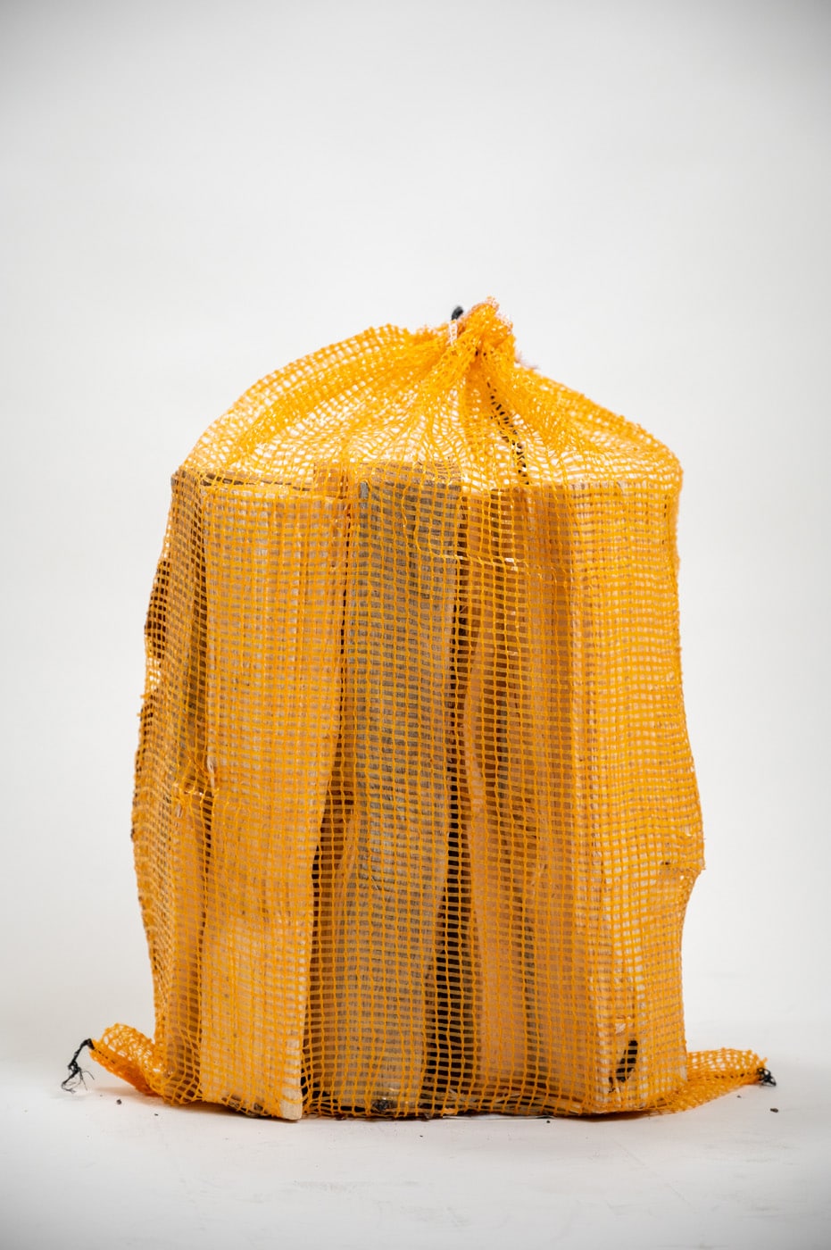A yellow mesh bag filled with firewood, labeled "Firewood 24/7 - Yellow Bag Full."